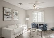 Thumbnail 6 of 28 - a living room with a white couch and a ceiling fan