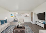 Thumbnail 3 of 22 - A living room with a white couch, a coffee table, and a television.