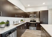 Thumbnail 2 of 24 - A modern kitchen with dark brown cabinets and stainless steel appliances.