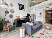 Thumbnail 5 of 26 - a living area with a couch chair and a kitchen in the background