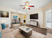 Thumbnail 9 of 33 - A living room with a beige couch, a coffee table, and a ceiling fan.