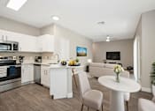Thumbnail 6 of 23 - A modern kitchen with a dining table and chairs.