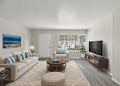 Thumbnail 25 of 29 - A living room with a couch, chair, ottoman, and television.
