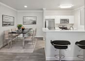 Thumbnail 2 of 20 - A kitchen with a bar stool and a dining table.
