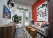 Thumbnail 3 of 25 - a living room with an orange accent wall and a gray couch