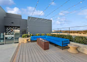 Thumbnail 19 of 31 - A modern outdoor seating area with a blue bench and wooden deck.