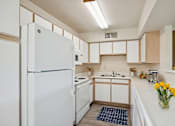 Thumbnail 1 of 22 - A white refrigerator stands in a kitchen with wooden cabinets and a sink.
