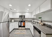 Thumbnail 21 of 29 - A modern kitchen with a stainless steel refrigerator and white cabinets.