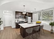 Thumbnail 2 of 15 - A modern kitchen with a curved island and bar stools.
