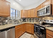 Thumbnail 2 of 21 - A kitchen with wooden cabinets and a granite countertop.