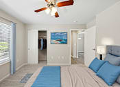 Thumbnail 22 of 29 - A bedroom with a bed, a ceiling fan, and a painting of a beach scene on the wall.