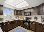 Thumbnail 2 of 33 - A kitchen with brown cabinets and a black stove top oven.