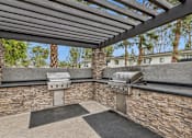 Thumbnail 14 of 17 - A patio with a grill and a stone wall.