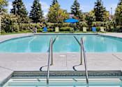 Thumbnail 11 of 20 - a swimming pool with a blue umbrella and chairs around it