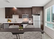 Thumbnail 1 of 15 - A modern kitchen with a table and chairs.