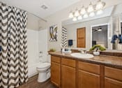 Thumbnail 6 of 21 - A bathroom with a brown counter top and a white toilet.