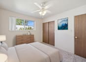 Thumbnail 8 of 22 - A bedroom with a large bed, a ceiling fan, and a painting on the wall.