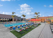 Thumbnail 18 of 31 - A large outdoor swimming pool area with loungers and umbrellas.