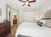 Thumbnail 7 of 21 - A bedroom with a large bed, a ceiling fan, and a wooden dresser.