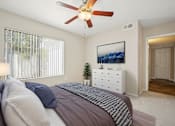 Thumbnail 14 of 33 - A bedroom with a bed, a ceiling fan, and a painting on the wall.