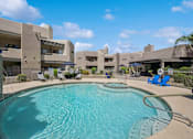 Thumbnail 8 of 21 - A swimming pool in front of a building with a blue sky in the background.