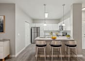 Thumbnail 4 of 28 - A modern kitchen with a bar stool at the island.