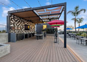 Thumbnail 22 of 31 - A wooden deck with a shaded area and tables.