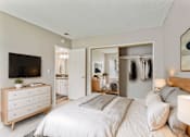Thumbnail 6 of 17 - A bedroom with a large bed and a dresser with a flat screen TV on top.