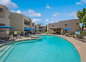 Thumbnail 1 of 21 - A large swimming pool in front of a building with a fence around it.