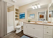 Thumbnail 4 of 25 - A bathroom with a white toilet, sink, and cabinets.