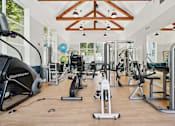 Thumbnail 17 of 27 - A gym with a variety of equipment including treadmills, stationary bikes, and weight machines.