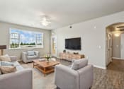 Thumbnail 3 of 30 - A living room with a grey couch, a wooden coffee table, and a flat screen TV.