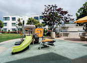 Thumbnail 8 of 23 - A playground with a yellow slide and a green slide.