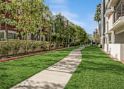 Thumbnail 28 of 28 - a walkway between two apartment buildings with green grass and trees