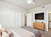 Thumbnail 7 of 30 - A bedroom with a large bed, a ceiling fan, and a TV mounted on the wall.