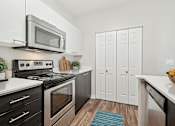 Thumbnail 3 of 27 - A modern kitchen with a black stove top oven and a silver microwave above it.
