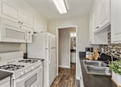 Thumbnail 2 of 17 - A kitchen with white cabinets and a brick backsplash.