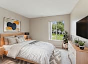 Thumbnail 4 of 17 - A bedroom with a large bed, a nightstand, and a window overlooking a green lawn.