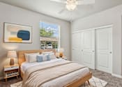 Thumbnail 10 of 30 - A bedroom with a large bed, two lamps, and a ceiling fan.