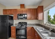 Thumbnail 4 of 27 - A kitchen with black appliances and wooden cabinets.