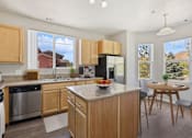 Thumbnail 1 of 23 - a kitchen with wooden cabinets and a table with a bowl of fruit