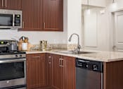Thumbnail 2 of 21 - A kitchen with brown cabinets and a granite countertop.