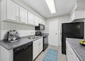 Thumbnail 1 of 30 - A kitchen with black appliances and white cabinets.