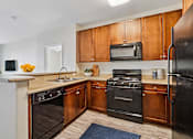 Thumbnail 1 of 24 - A kitchen with black appliances and wooden cabinets.