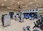 Thumbnail 21 of 38 - A gym with a variety of exercise equipment including treadmills, stationary bikes, and weight machines.