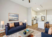 Thumbnail 4 of 28 - A living room with a blue couch and a painting on the wall.