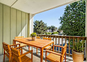 Thumbnail 11 of 27 - A wooden table and chairs on a balcony with a potted plant.