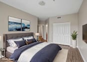 Thumbnail 11 of 27 - A bedroom with a large bed and a painting on the wall.