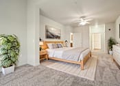 Thumbnail 6 of 19 - A bedroom with a bed, dresser, and ceiling fan.