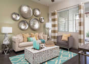 Thumbnail 5 of 21 - A living room with a sofa, armchair, and decorative wall pieces.